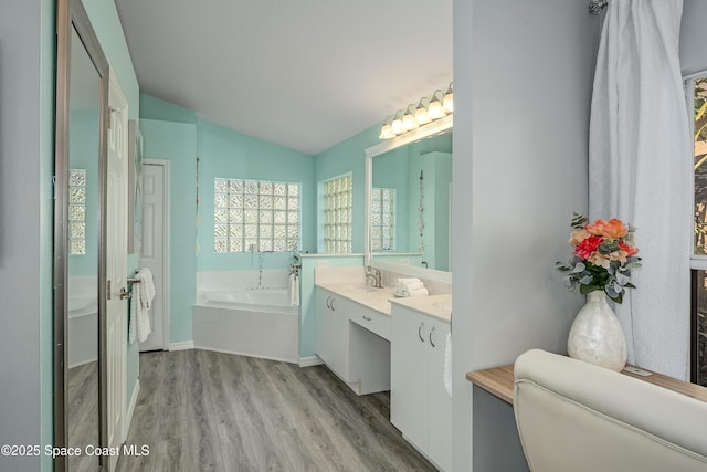 bathroom featuring a bathing tub, vanity, wood-type flooring, and vaulted ceiling