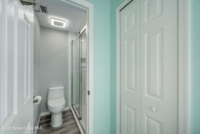 bathroom featuring a textured ceiling, hardwood / wood-style flooring, toilet, and a shower with shower door