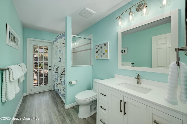 bathroom featuring hardwood / wood-style flooring, vanity, curtained shower, and toilet