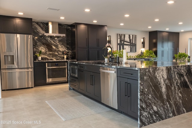 kitchen with appliances with stainless steel finishes, sink, dark stone countertops, and wall chimney exhaust hood