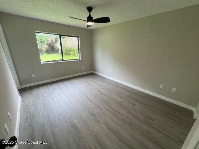 spare room with ceiling fan and dark wood-type flooring