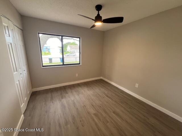 unfurnished bedroom with ceiling fan, a closet, and dark wood-type flooring