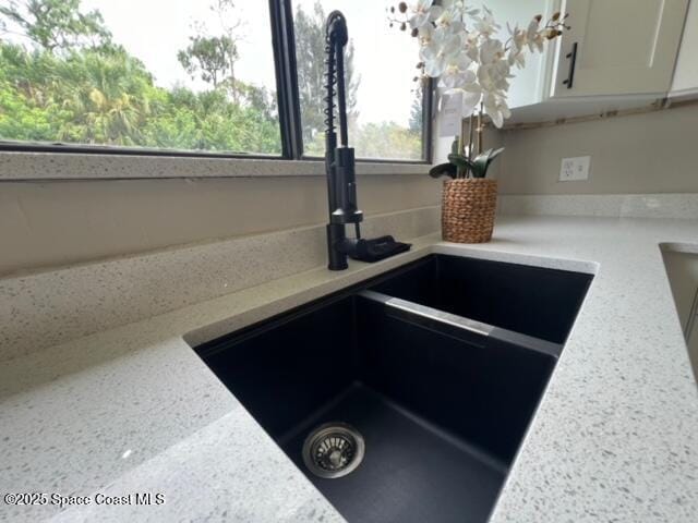 details with light stone counters, white cabinetry, and sink