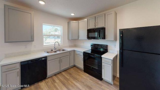 kitchen featuring light wood-type flooring, sink, gray cabinets, and black appliances