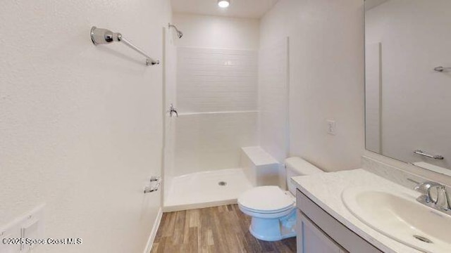 bathroom with wood-type flooring, vanity, toilet, and walk in shower