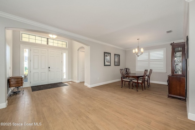 foyer entrance featuring a notable chandelier, crown molding, and light hardwood / wood-style flooring