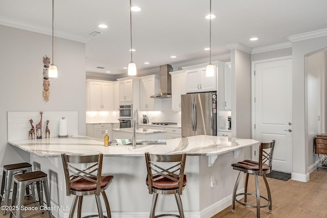 kitchen featuring pendant lighting, a kitchen bar, wall chimney range hood, and stainless steel refrigerator