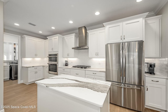 kitchen with a center island, white cabinets, wall chimney exhaust hood, light stone countertops, and appliances with stainless steel finishes