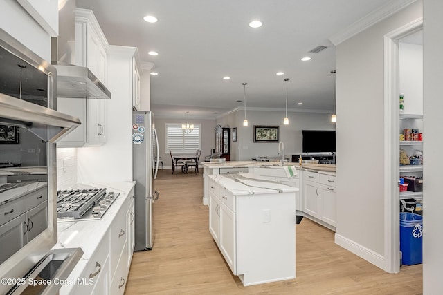 kitchen with pendant lighting, appliances with stainless steel finishes, a kitchen island, light stone counters, and white cabinetry