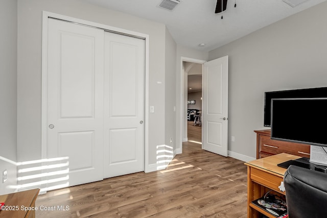 home office with light wood-type flooring and ceiling fan