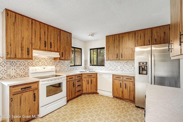 kitchen featuring sink, white appliances, decorative backsplash, and a textured ceiling