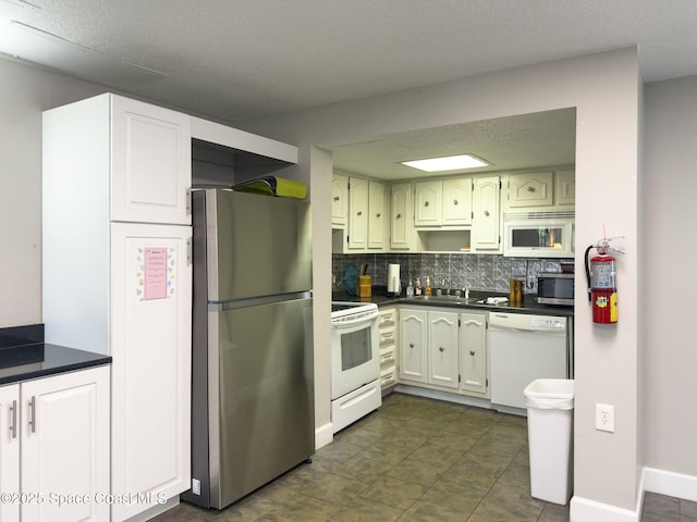 kitchen with tasteful backsplash, white cabinets, appliances with stainless steel finishes, and sink