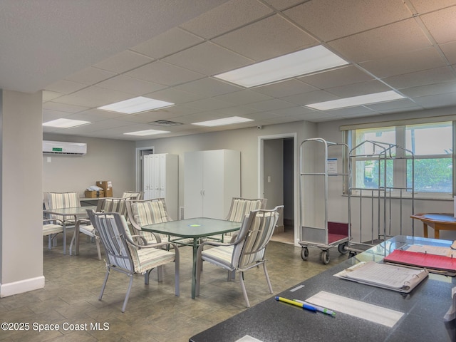 dining space with a wall unit AC and a drop ceiling