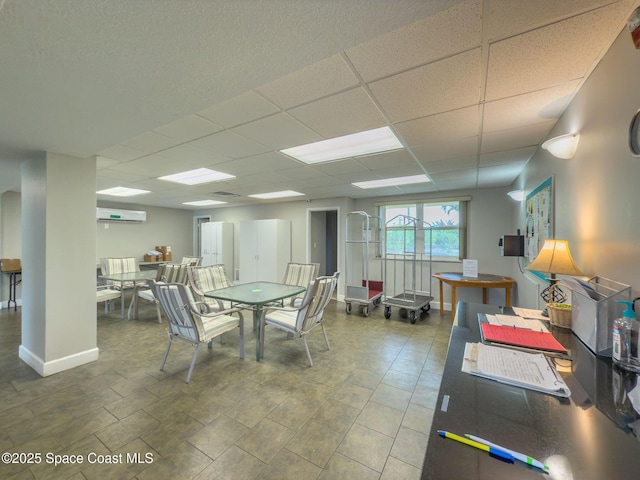 dining room with a wall mounted AC and a paneled ceiling