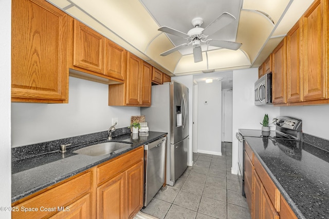 kitchen with appliances with stainless steel finishes, dark stone countertops, sink, ceiling fan, and light tile patterned floors