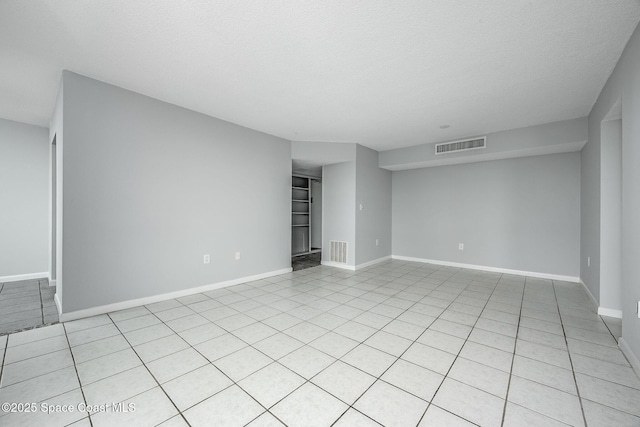 spare room featuring a textured ceiling and light tile patterned flooring