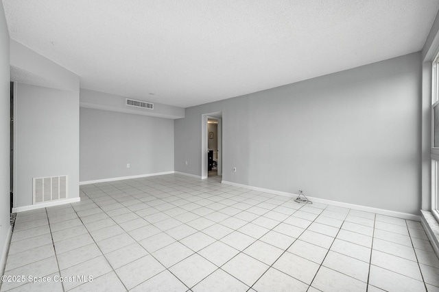 tiled empty room with a textured ceiling