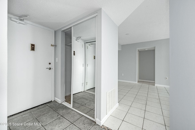 hallway featuring light tile patterned floors and a textured ceiling