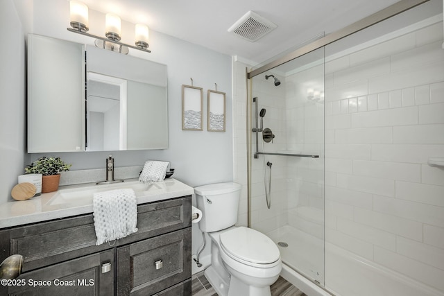 bathroom with a shower with shower door, hardwood / wood-style flooring, toilet, and vanity