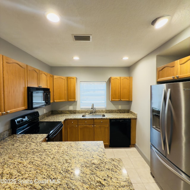 kitchen with light stone countertops, a textured ceiling, sink, black appliances, and light tile patterned flooring