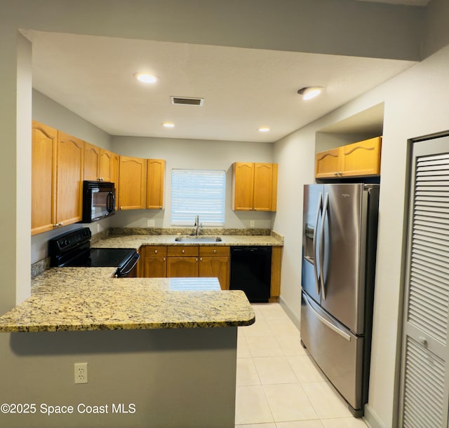 kitchen with kitchen peninsula, light stone countertops, sink, black appliances, and light tile patterned floors