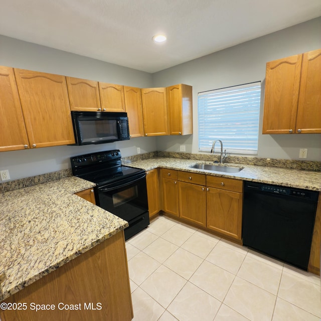 kitchen with light stone counters, sink, light tile patterned flooring, and black appliances