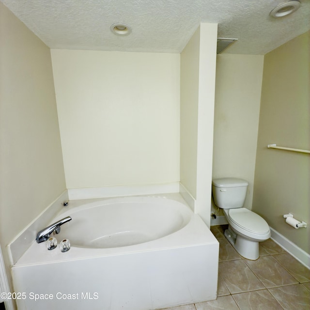 bathroom featuring tile patterned flooring, a bath, a textured ceiling, and toilet