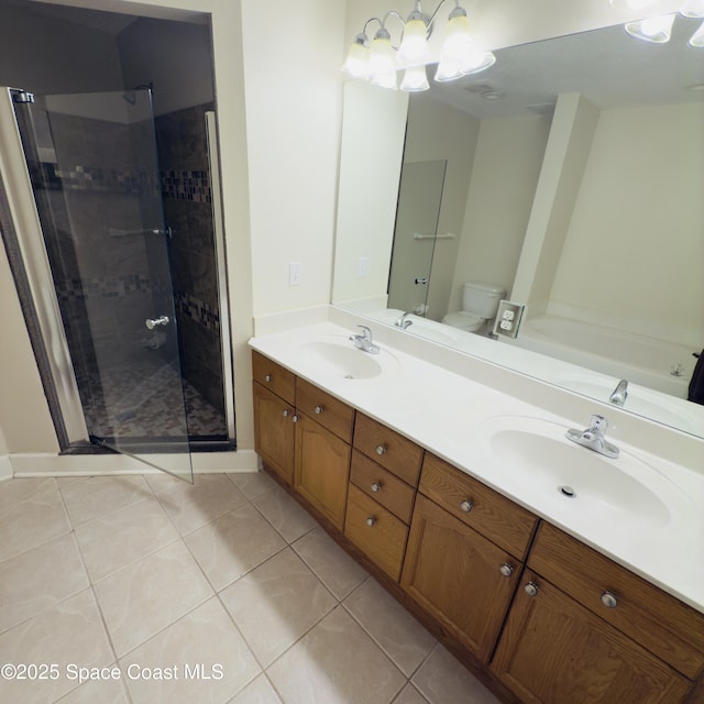 bathroom with toilet, vanity, tiled shower, and tile patterned floors