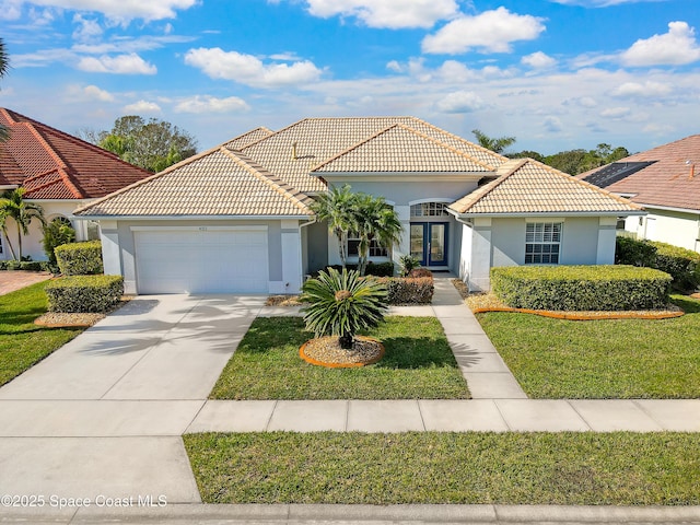 mediterranean / spanish-style house featuring french doors, a garage, and a front lawn