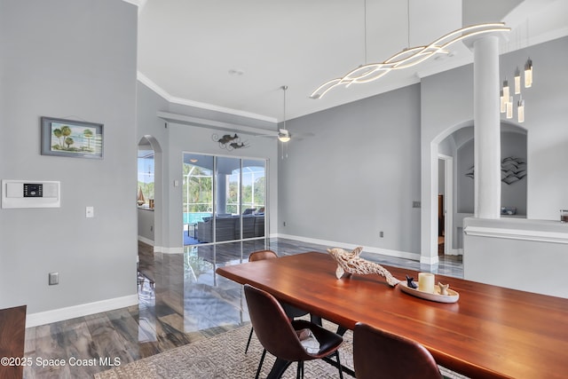 dining room featuring a high ceiling, dark hardwood / wood-style floors, ceiling fan, and crown molding