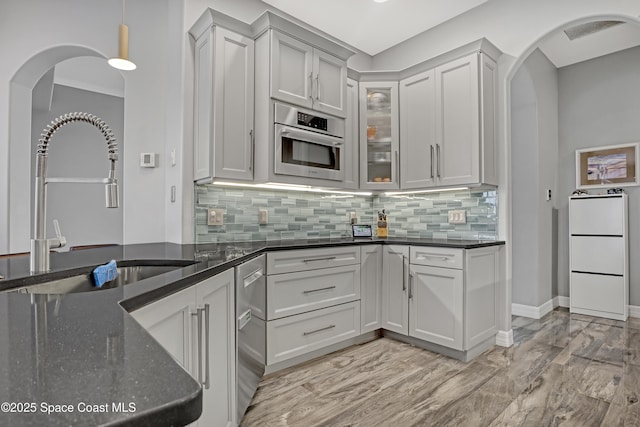 kitchen featuring decorative backsplash, pendant lighting, sink, and dark stone countertops