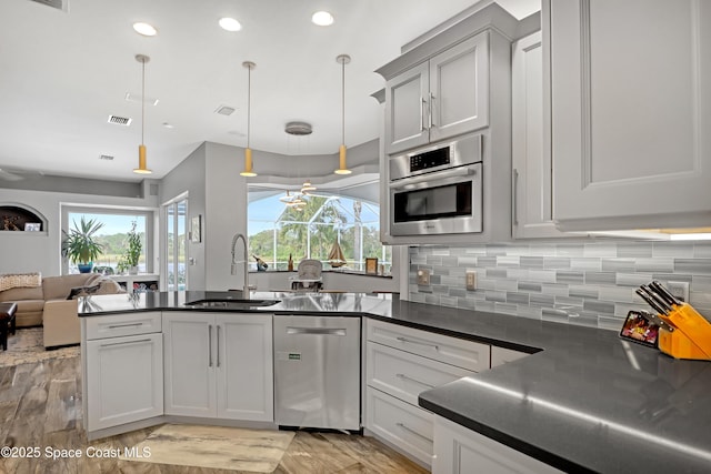 kitchen with tasteful backsplash, hanging light fixtures, stainless steel appliances, and sink