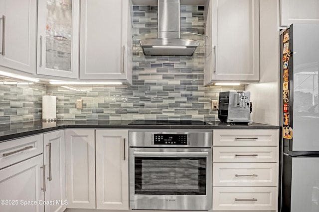 kitchen featuring decorative backsplash, appliances with stainless steel finishes, white cabinetry, and wall chimney exhaust hood