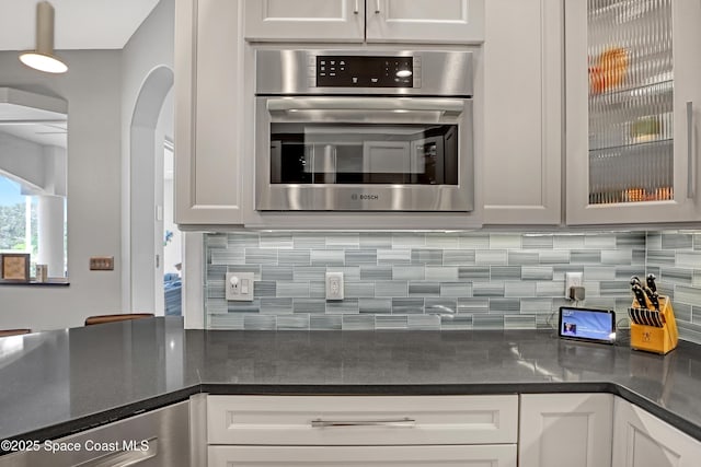 kitchen featuring white cabinets, oven, and backsplash