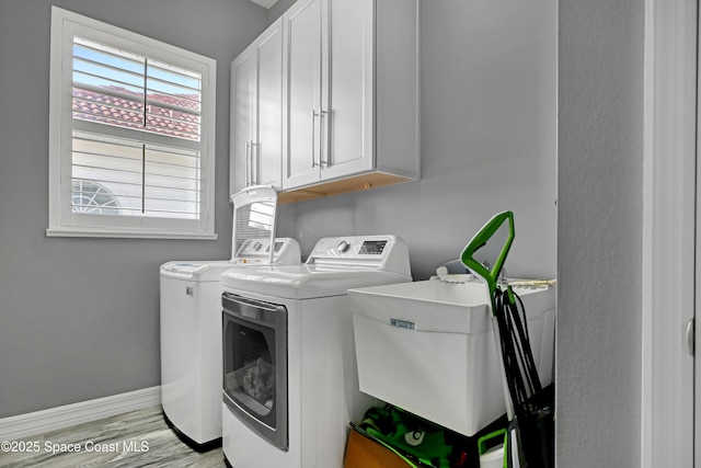 washroom featuring cabinets, separate washer and dryer, sink, and light hardwood / wood-style flooring