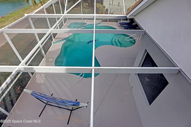 view of pool featuring glass enclosure and a water view