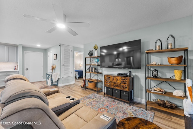 living room with a textured ceiling, light hardwood / wood-style flooring, and ceiling fan