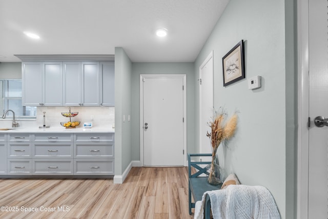 interior space with sink, gray cabinetry, backsplash, and light hardwood / wood-style flooring