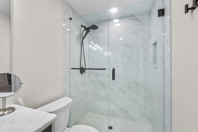 bathroom featuring vanity, a shower with shower door, and toilet