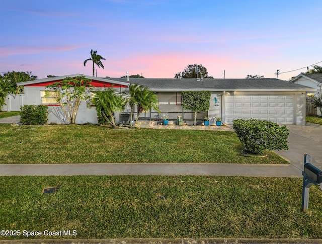 single story home with cooling unit, a garage, and a yard