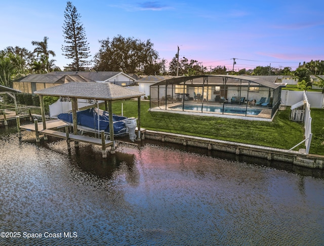 dock area featuring a water view, glass enclosure, and a lawn