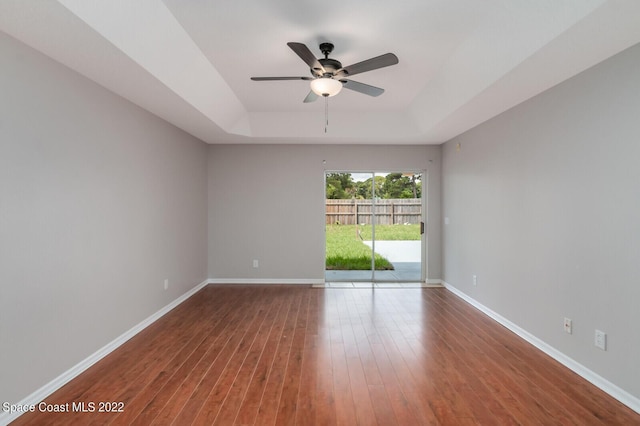 unfurnished room with hardwood / wood-style floors, ceiling fan, and a tray ceiling