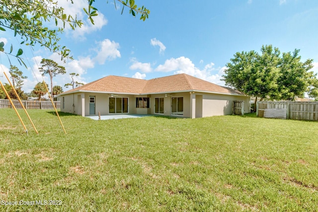 rear view of house with ceiling fan, a yard, and a patio