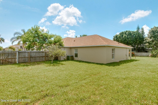 rear view of house featuring a yard and central AC unit