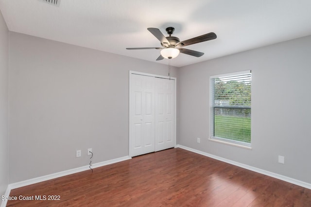 unfurnished bedroom with ceiling fan, dark hardwood / wood-style flooring, and a closet