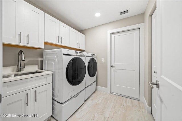 washroom with washer and dryer, sink, and cabinets