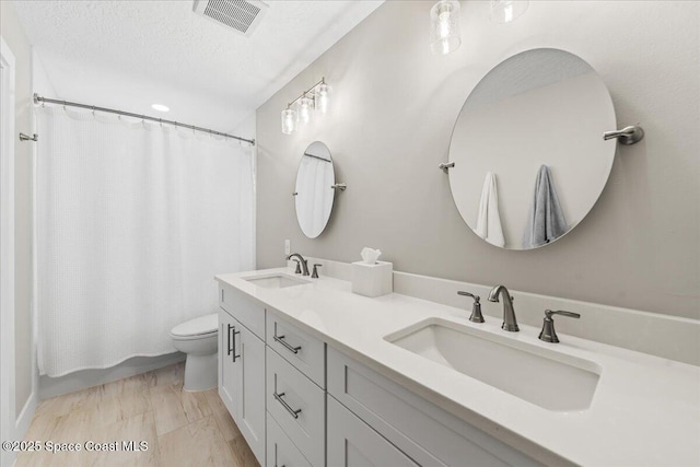 full bathroom with toilet, a textured ceiling, shower / bath combo, and vanity