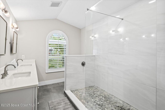 bathroom featuring tiled shower, a textured ceiling, lofted ceiling, and vanity