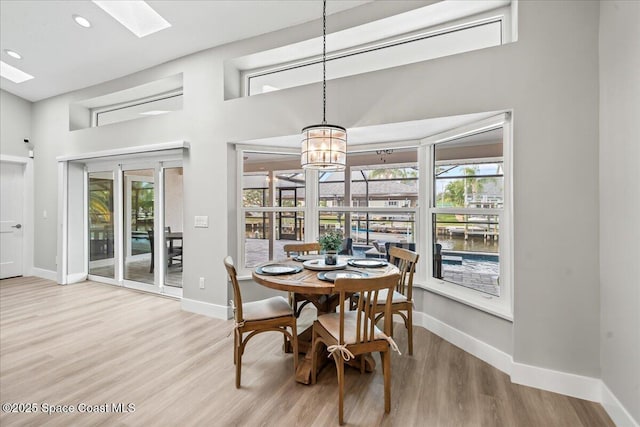 dining room featuring light hardwood / wood-style floors, a skylight, an inviting chandelier, and plenty of natural light