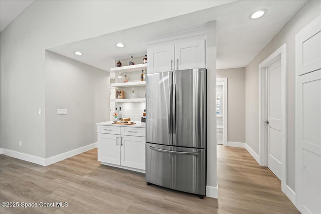 kitchen with white cabinetry, light hardwood / wood-style flooring, stainless steel fridge, and tasteful backsplash